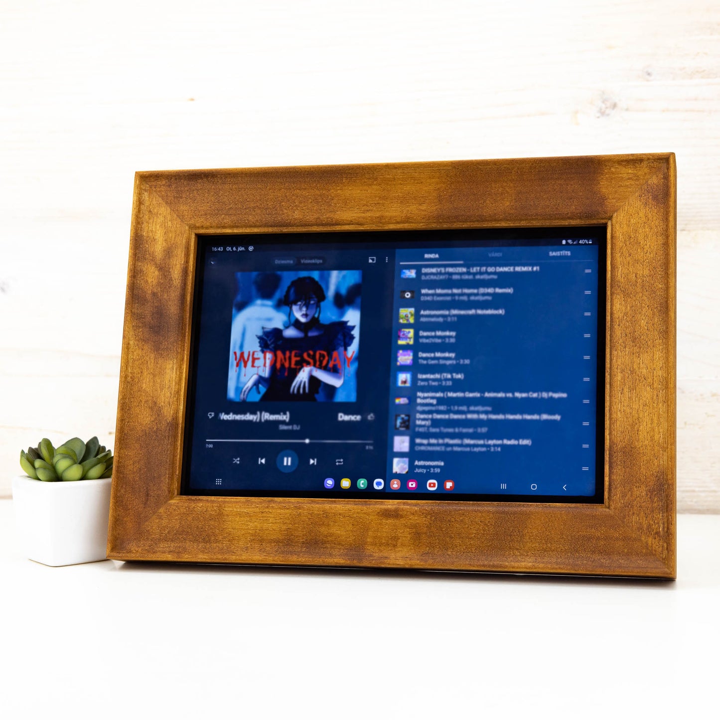 Brown wooden frame holding an iPad showing a music playlist on the screen.