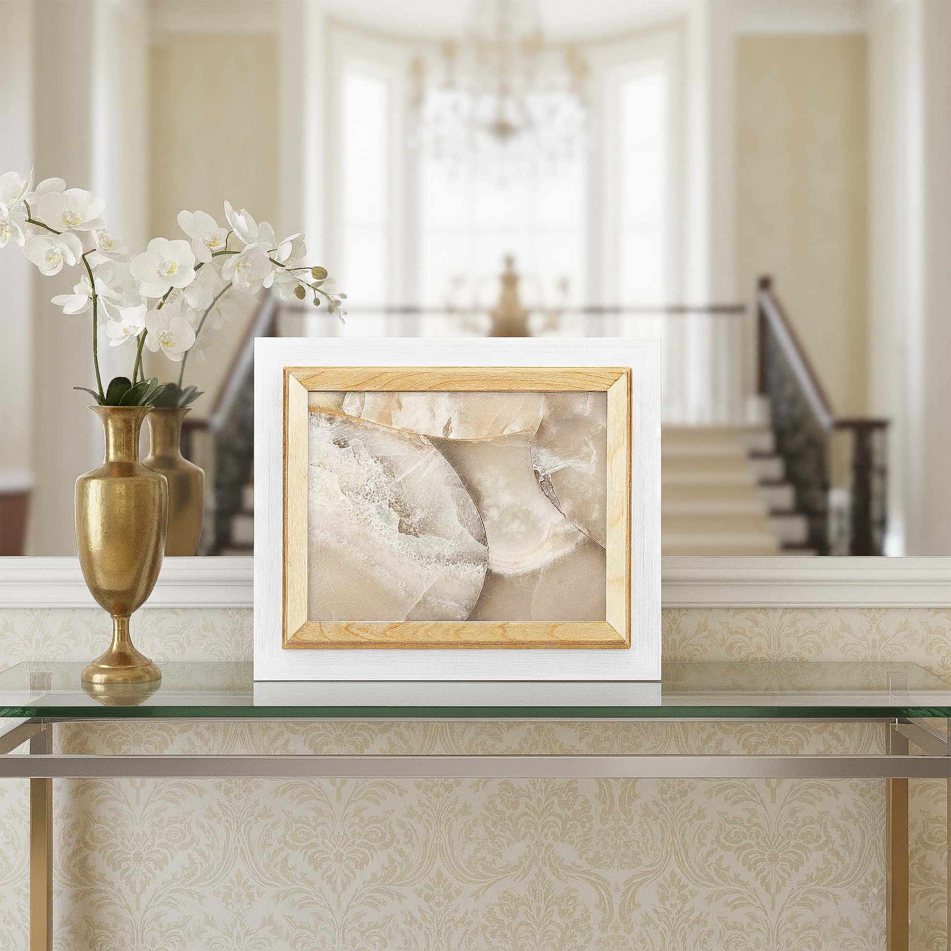 Framed artwork on a table with decorative vases and flowers in a home setting