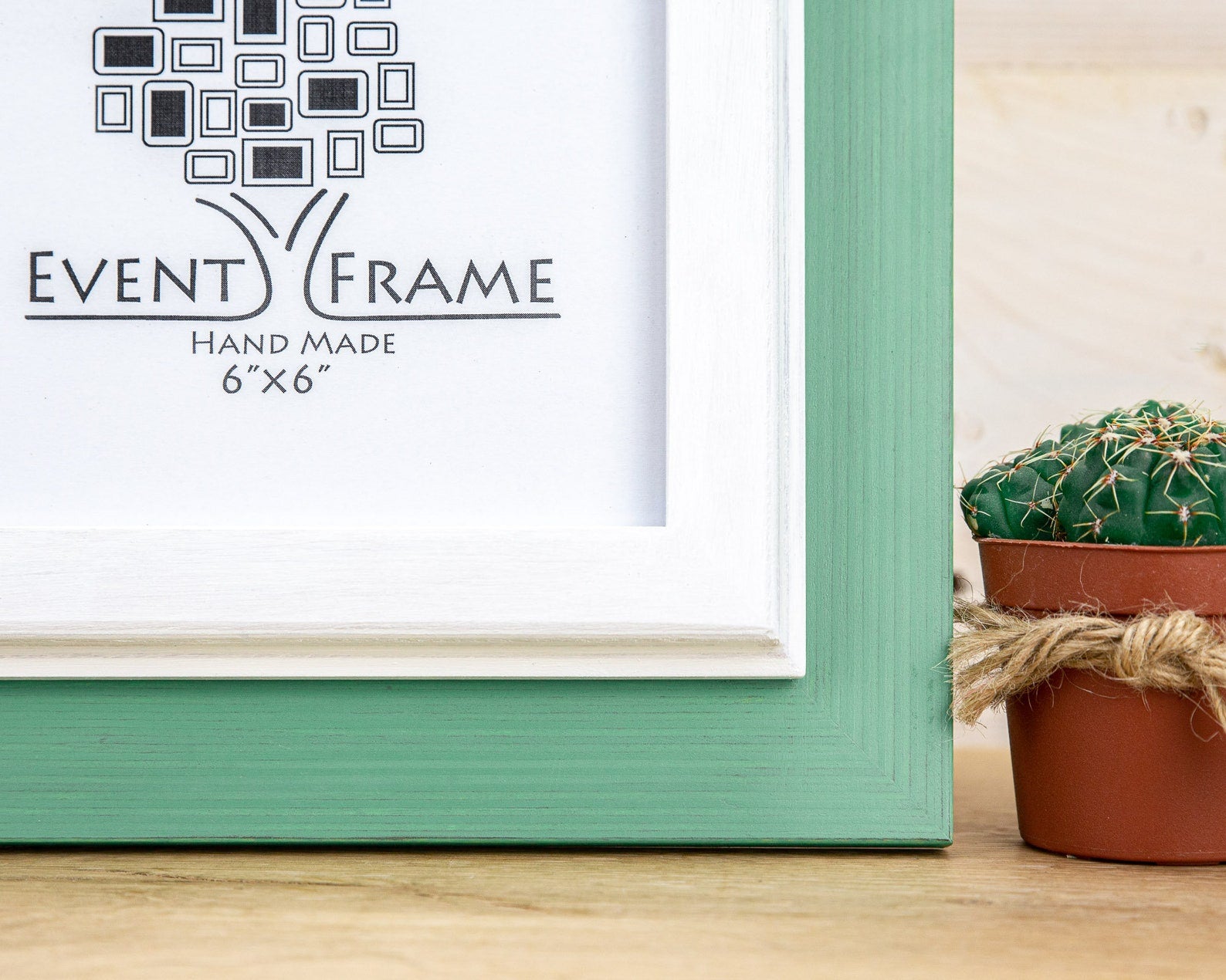 Green picture frame with 'Event Frame' branding on a wooden surface next to a potted cactus. Grey and white rustic birch frame with handmade charm and clean contrast. Eco-finished and perfect for art, photos, or calm modern wall décor.