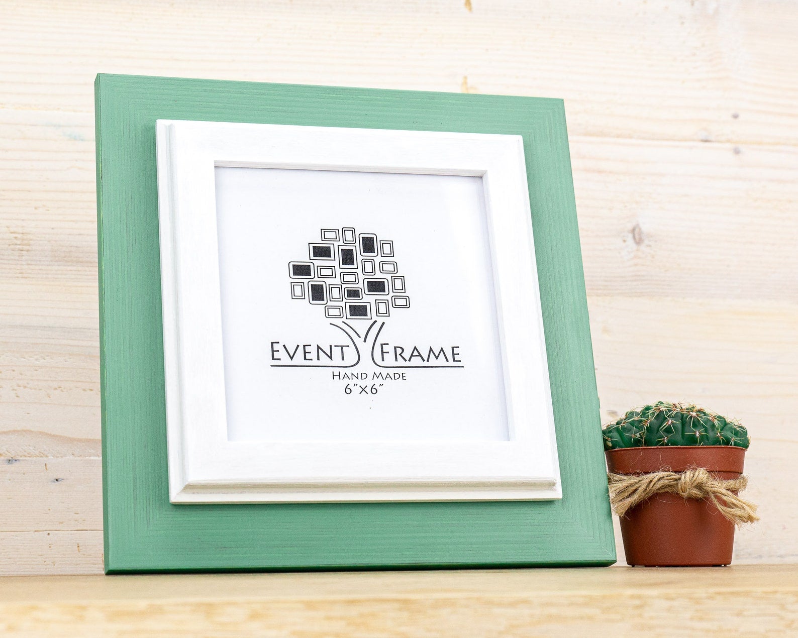 Green picture frame with 'Event Frame' logo on a wooden surface with a small potted plant. Grey and white rustic birch frame with handmade charm and clean contrast. Eco-finished and perfect for art, photos, or calm modern wall décor.