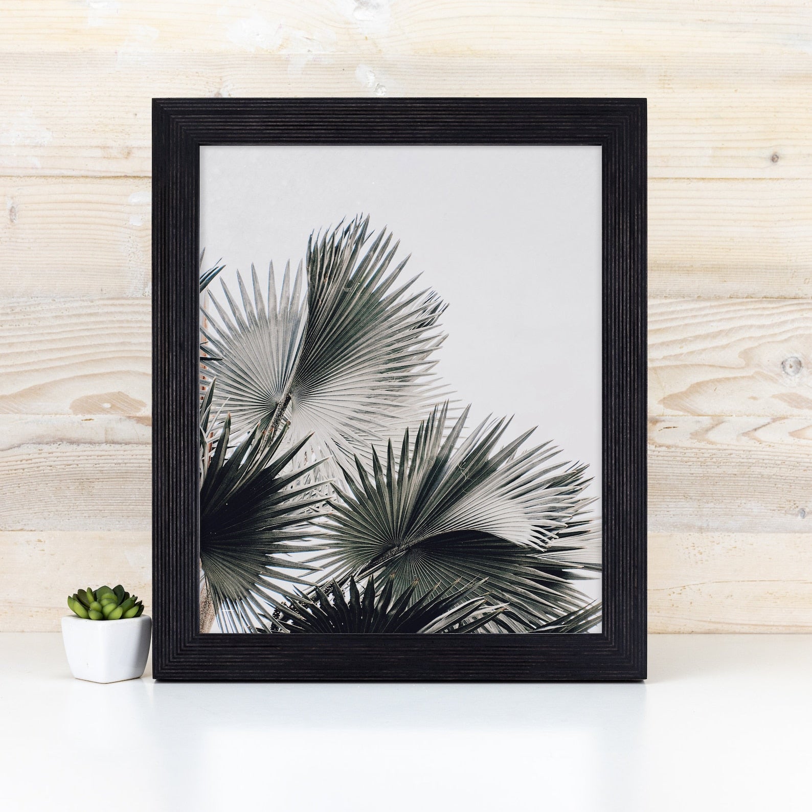 Framed artwork of palm leaves on a white background with a wooden wall and small plant in the foreground. Black Picture Frame, Wooden Photo Frame, Rustic Stripy Design Frame, Dark Academia Decor,Diploma Frame A1 A3 A4 8x10 11x14 12x18 18x24 20x30