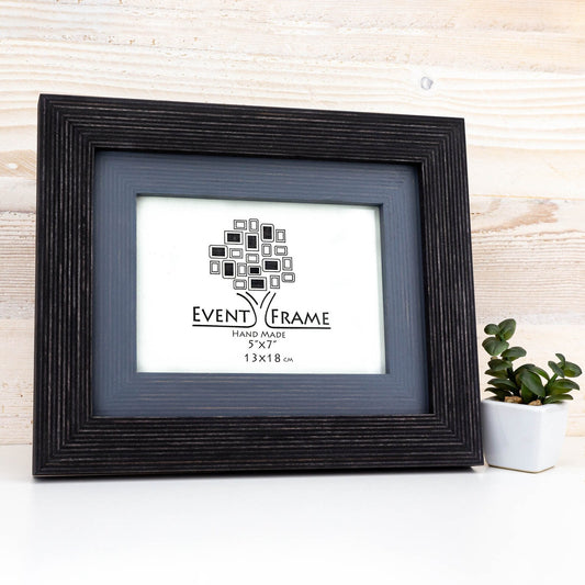 Black and grey picture frame with 'Event Frame' logo on a light wooden background