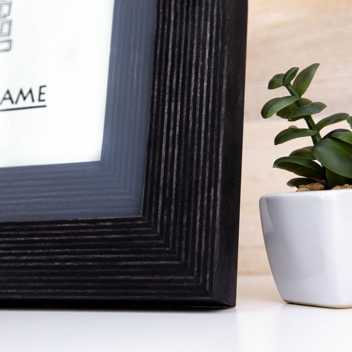Black textured picture frame on a white surface with a plant in the background. Black + Grey Handmade Picture Frame, Photo Frame with Wooden Mat, Two Tone Poster Wall Frame, Custom Sizes A1 A2 5x7 8x10 18x24 24x36 20x30