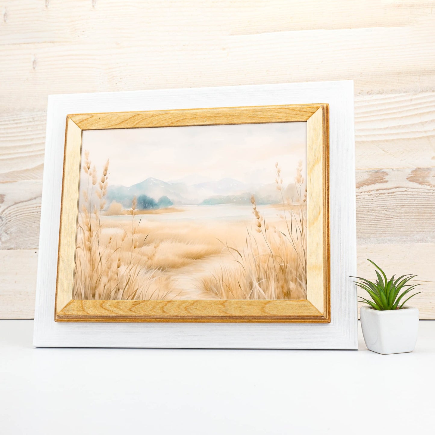 Framed artwork of a landscape with tall grass and mountains on a wooden surface. White + Natural Custom Wooden Frame, Handmade Double Color Photo Frame, Modern Wall Frame, Poster Frame A1 A2 A3 A4 11x14 12x18 20x30 24x36