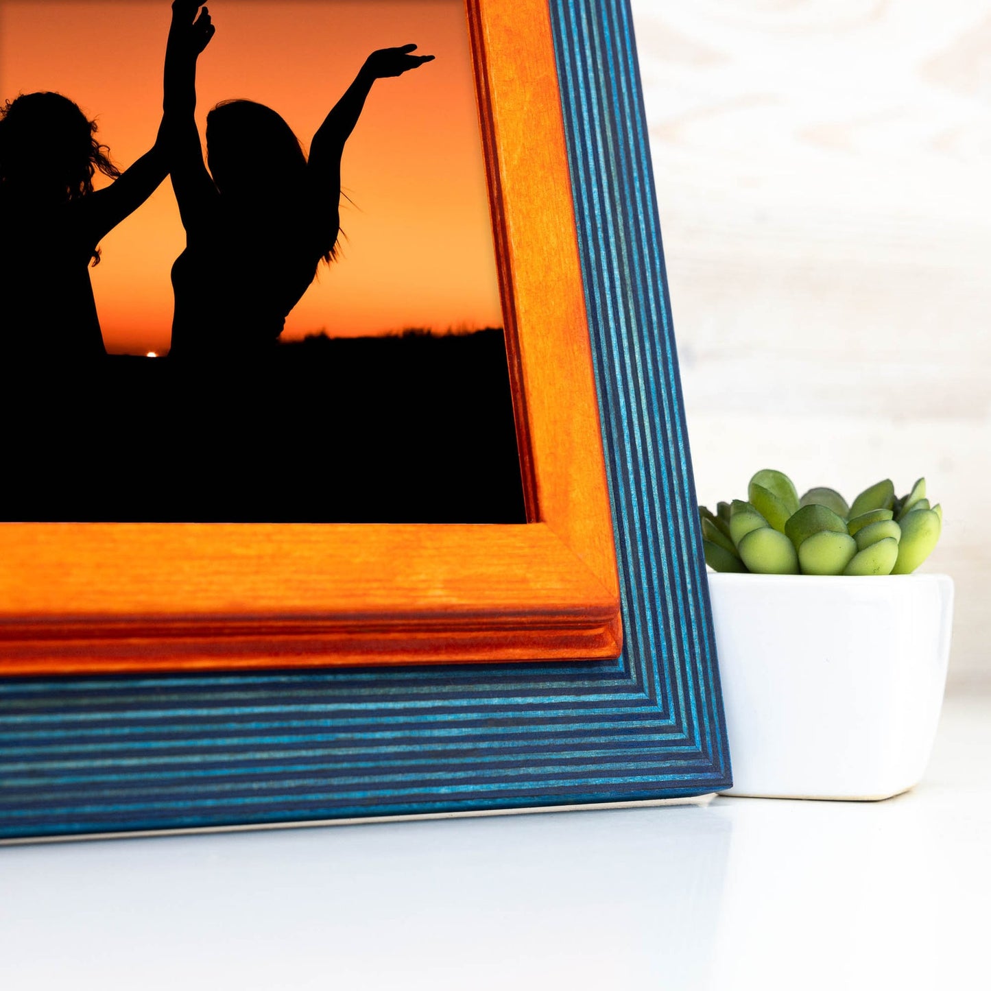 Framed silhouette of two people against a sunset with a small plant in the background. Add rustic elegance with this grey + white birch frame. Handmade and built to last, ideal for artwork, photo décor, or Scandi-inspired homes.