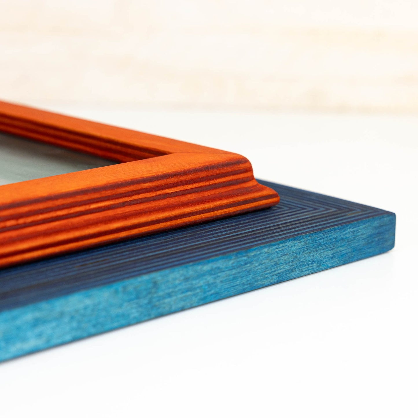 Close-up of an orange and blue rectangular object on a white background. Add rustic elegance with this grey + white birch frame. Handmade and built to last, ideal for artwork, photo décor, or Scandi-inspired homes.