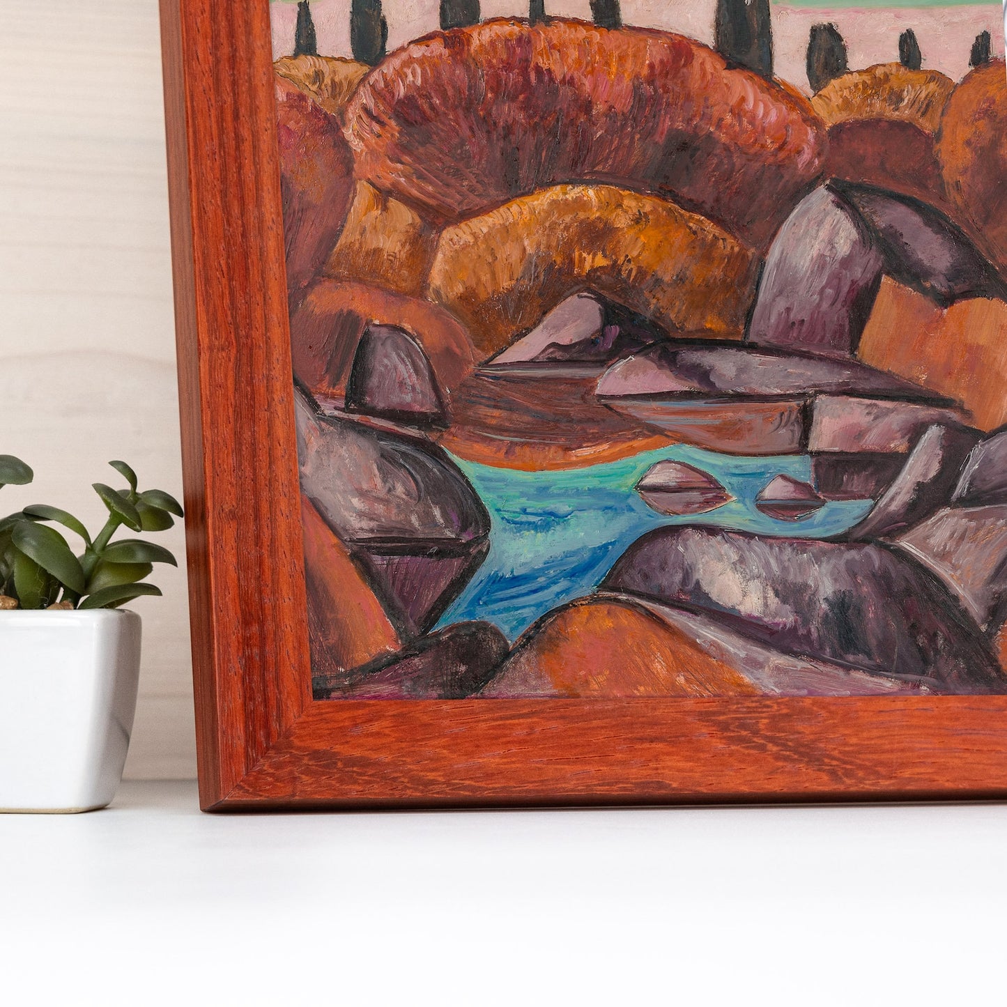 Framed artwork of a landscape with rocks and water on a white surface. Handmade alder hardwood frame with rich brown tones and red accents. Finished in natural oil, it adds warmth and charm to your artwork or photos.