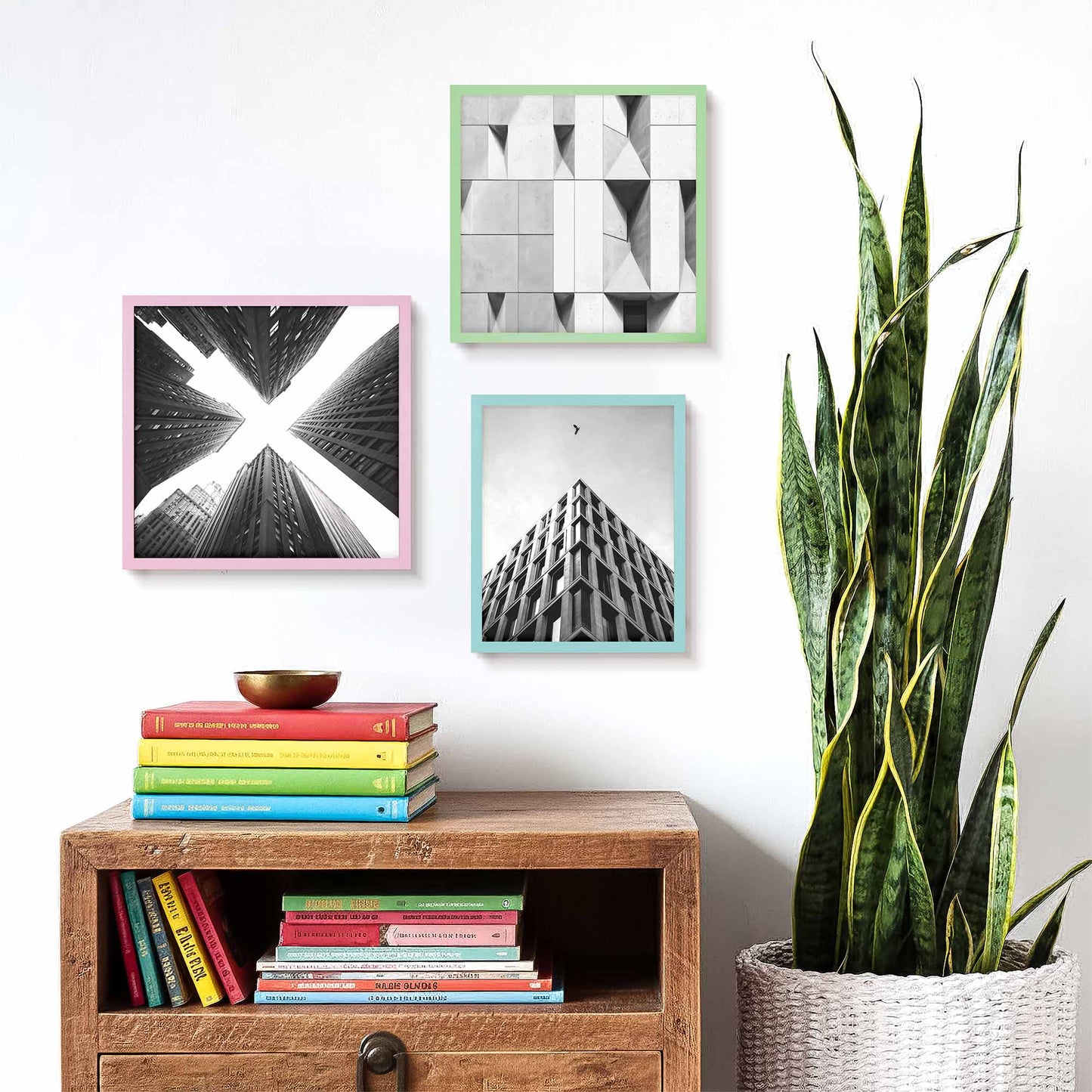 Decorative wall with framed art and photo picture frames, books on a wooden shelf, and a plant.
