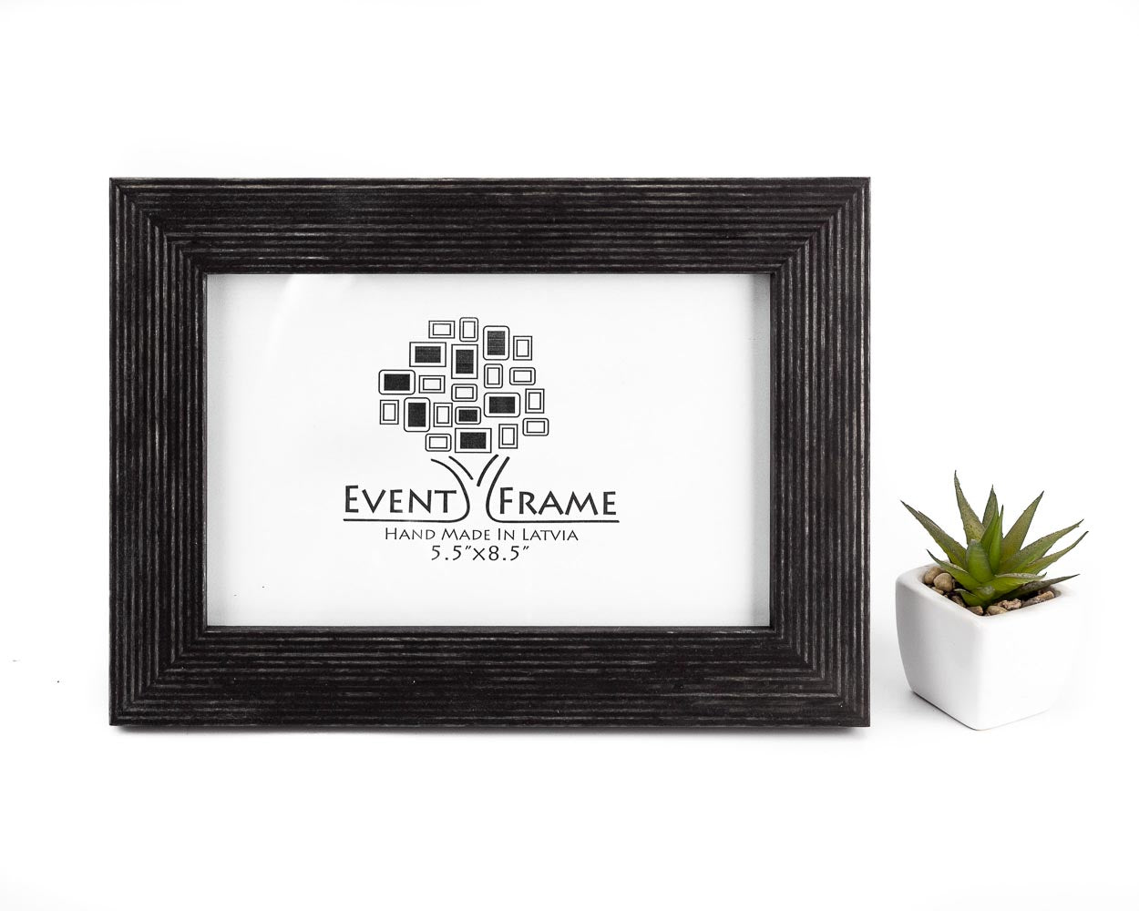 A black solid birch hardwood picture frame with a unique stripy design, displayed with a small potted plant to the side.