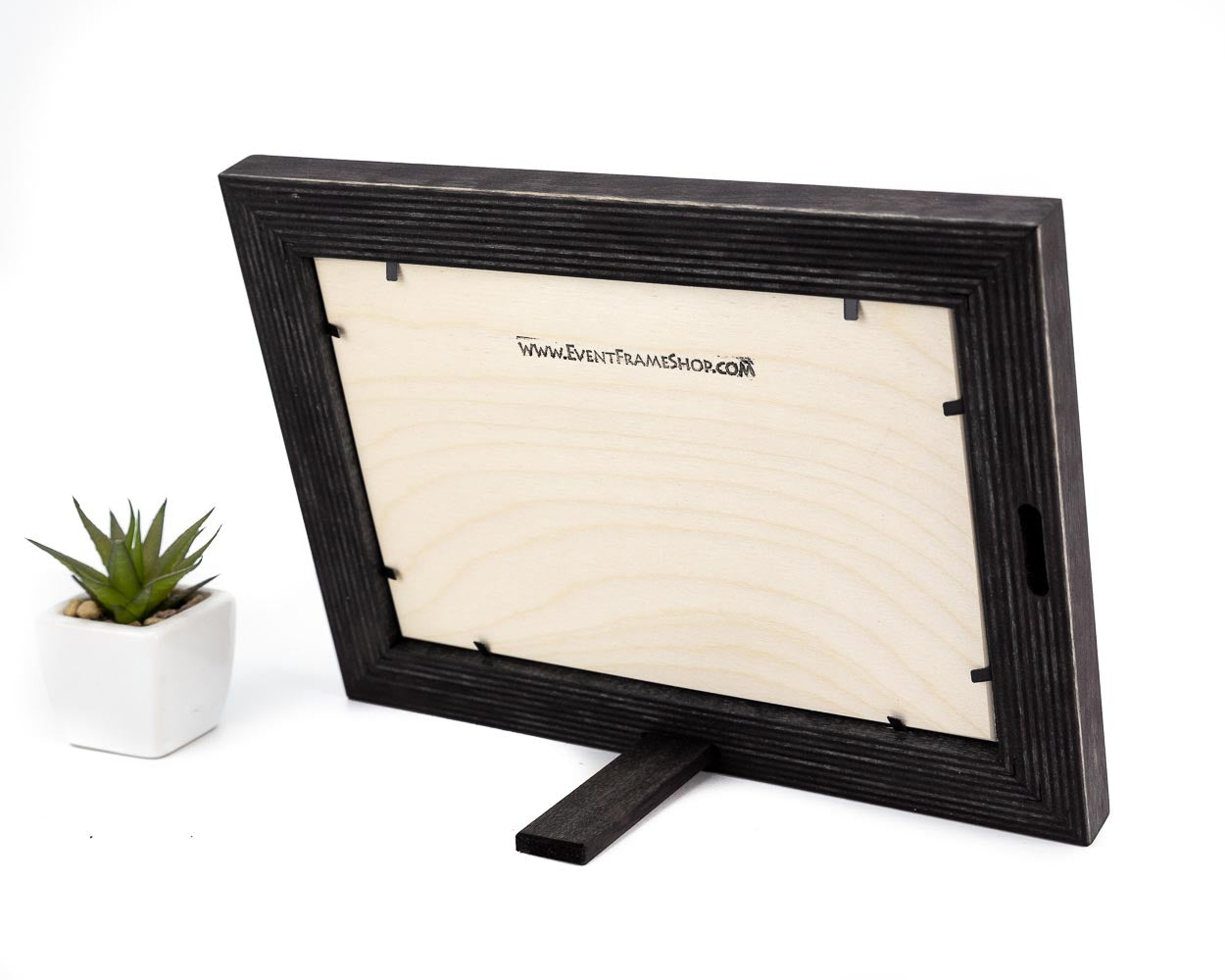A black solid birch hardwood picture frame with a unique stripy design, displayed with a small potted plant to the side.