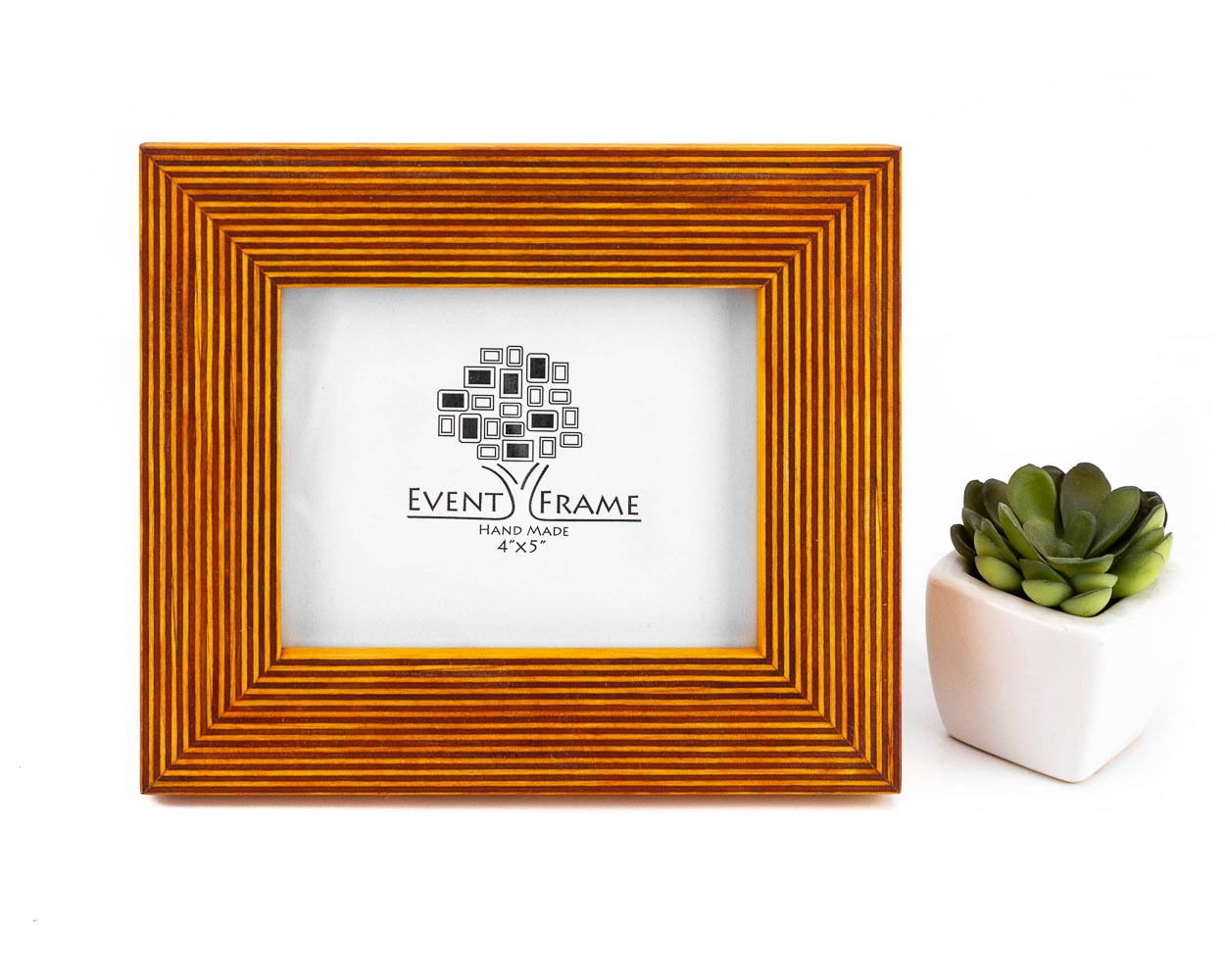 A yellow solid birch hardwood picture frame with a unique stripy design, branded with 'Event Frame' on the front, displayed alongside a white vase with a green plant.