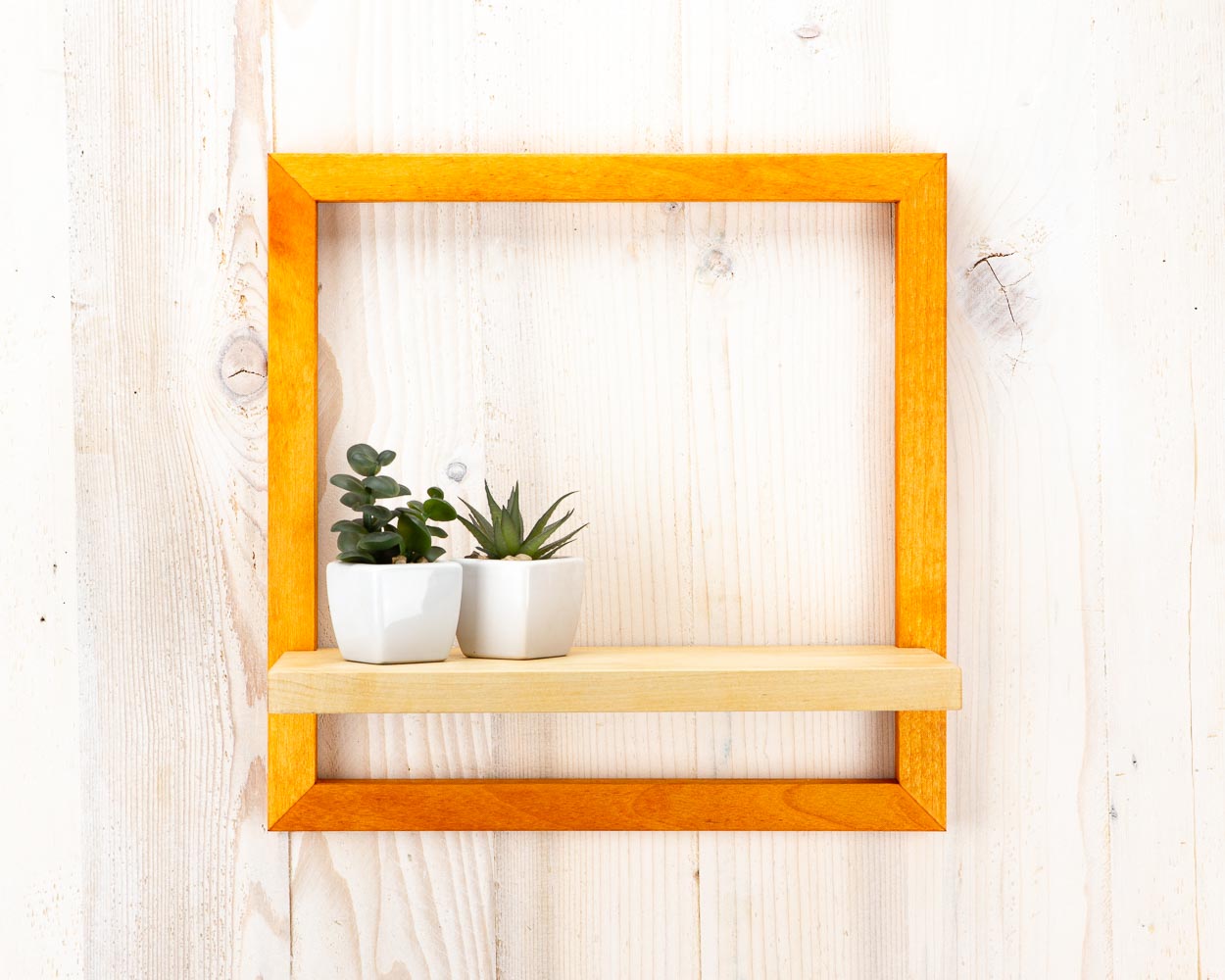 Orange wooden quality picture frame holding two planters, used in a home or office setting.