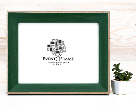 A dark green classic style picture frame made of solid birch hardwood, displayed on a wooden background with a white mat and black text area for the event frame brand.