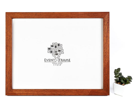 A solid African Sapele hardwood picture frame in its natural color, with a white mat and a clear acrylic cover, displaying a logo in the center, placed on a white background with a small potted plant to the side. Wall Art Picture Frame From Sapele Hardwood, Modern Style Poster Frame, Any Size 8x10, 11x14, A5, A4, A3, 10x12, 8,5x11, 8x12, 5x7, 4x6, 8x8