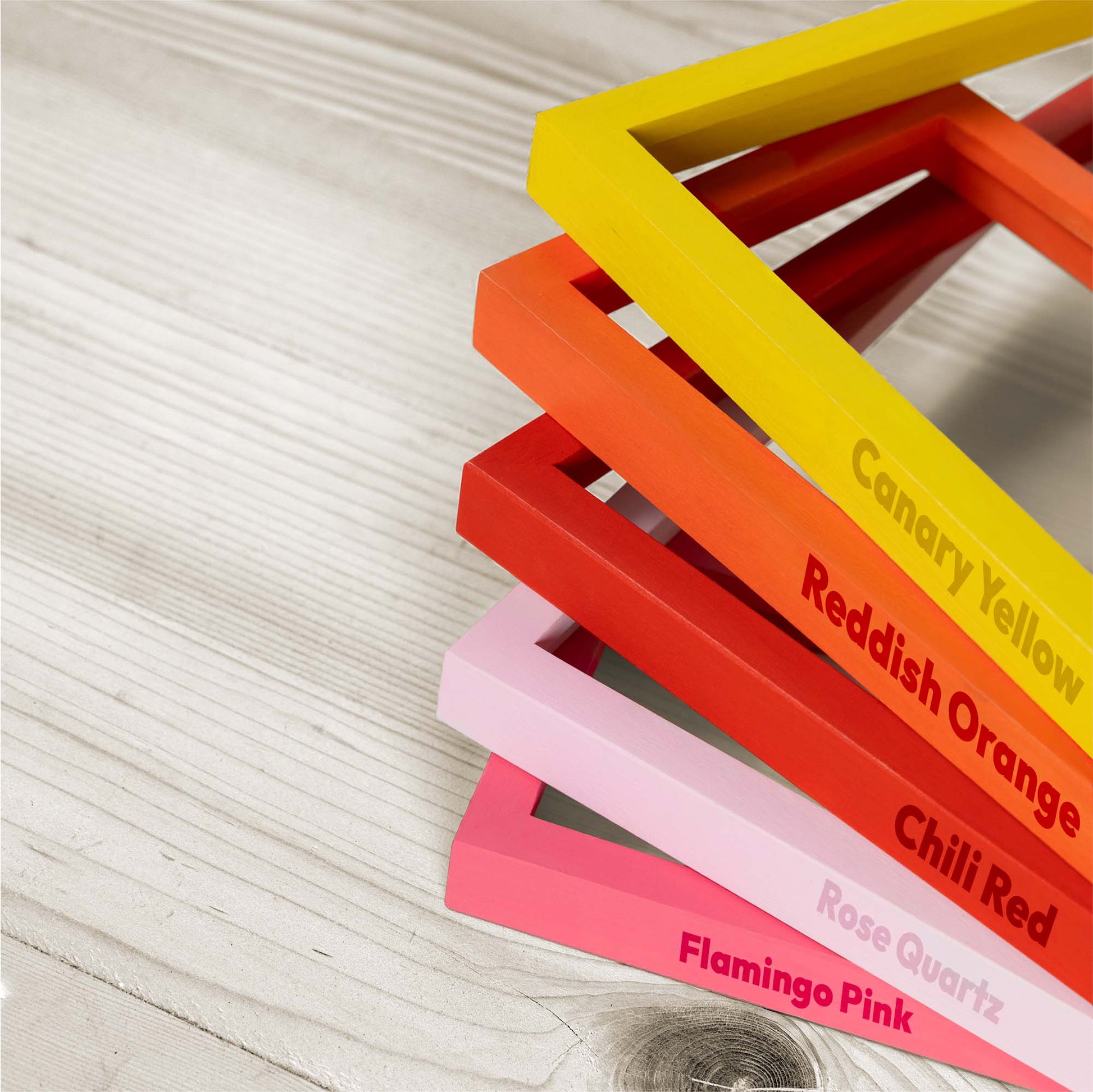Color swatches on wooden photo picture frames labeled with color names on a wooden surface