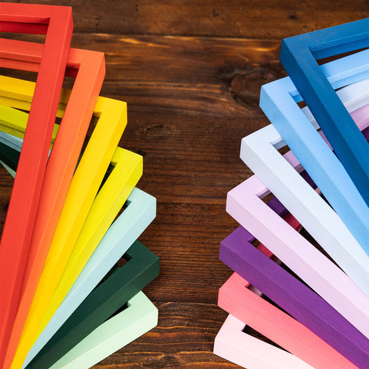 Colorful wooden frames stacked on a wooden surface. Colorful Picture Frames: Super Thin Edge, Custom Size, Vibrant and Pastel Frames