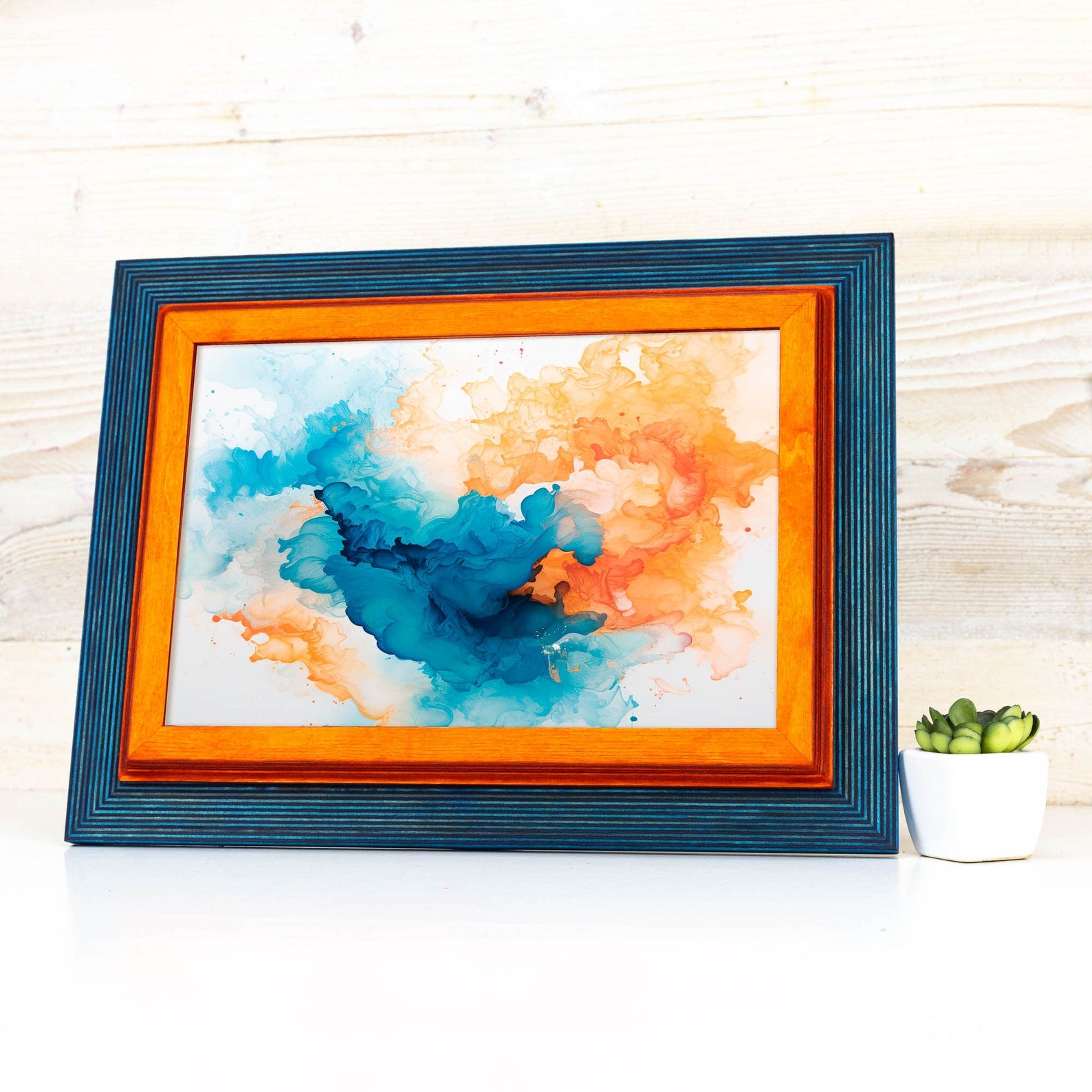 Framed abstract art with blue and orange colors on a wooden surface. Add rustic elegance with this grey + white birch frame. Handmade and built to last, ideal for artwork, photo décor, or Scandi-inspired homes.