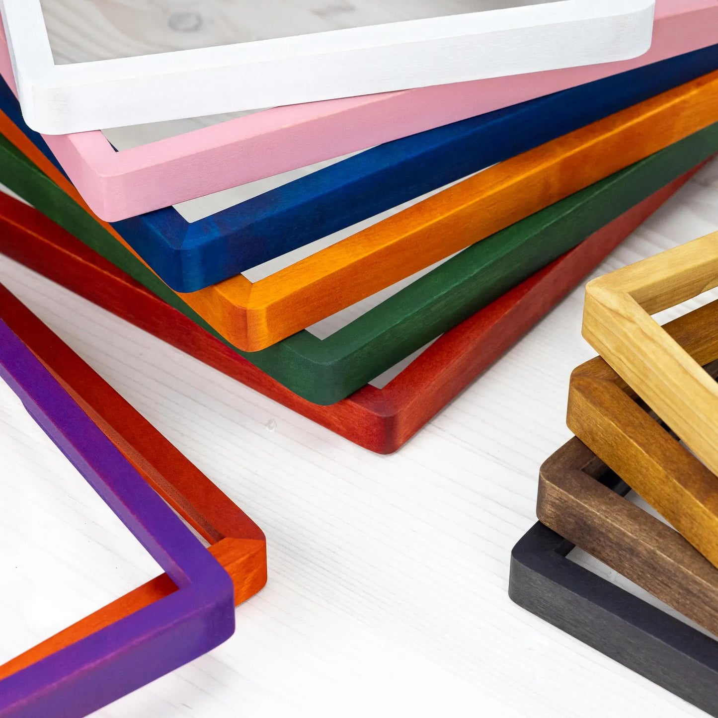 Close-up of corners of wooden picture frames in various colors and stains, showing variety.