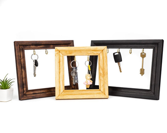 Wooden key holder frame in three different color variations in brown, natural and black. 